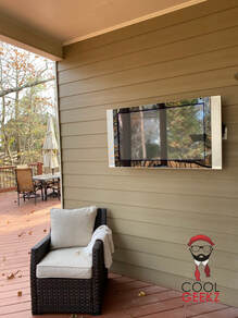 flat tv mounted outside onto home with chair in front by Cool Geekz